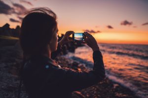 woman filming the sunrise of the sea